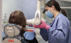 dental assistant preparing an x-ray while someone is sitting in a medical chair