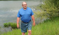 Man wearing a blue shirt, walking outside. 