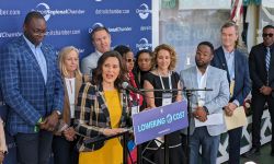 Gov. Gretchen Whitmer speaking into a microphone, many people standing behind her