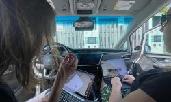 Kelly House and Paula Gardner working on their laptops in an EV car