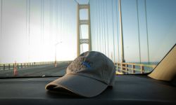 A Bridge Michigan hat on the car dashboard, the Mackinaw Bridge in the background