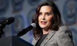 Gov. Gretchen Whitmer, wearing a grey jacket, speaks into a microphone