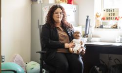 Fatima Barba sitting in a chair, holding a doll. She's in an office