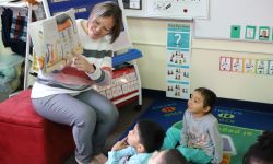 A teacher reading a book to young children in a classroom