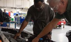 Two people looking inside the hood of the car