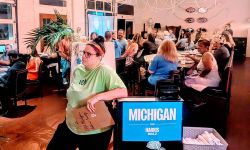 Pleasant Ridge resident Jordan Weisman stands next to a Michigan Harris-Walz sign in a roonm