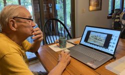 John Doyle sitting at a table looking a laptop