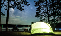 A green tent in the woods at night