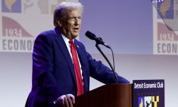 Donald Trump speaking into a microphone at the Detroit Economic Club