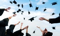 Graduating students hands throwing graduation caps in the air.