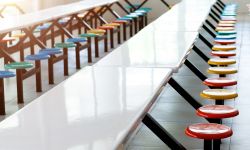 Clean school cafeteria with white tables and colorful seats