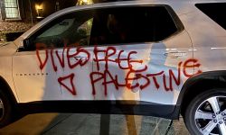 A white car spray painted in red with an inverted triangle. 