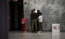 A voter casts a ballot at Owen Jax Community Center in Warren, Mich. Two kids stand next him