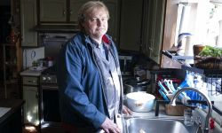 JT Anderson near the kitchen sink in his home. He is wearing a blue jacket.