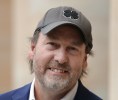 Headshot of a smiling bearded man wearing a baseball-style cap with a four-leaf clover on it.