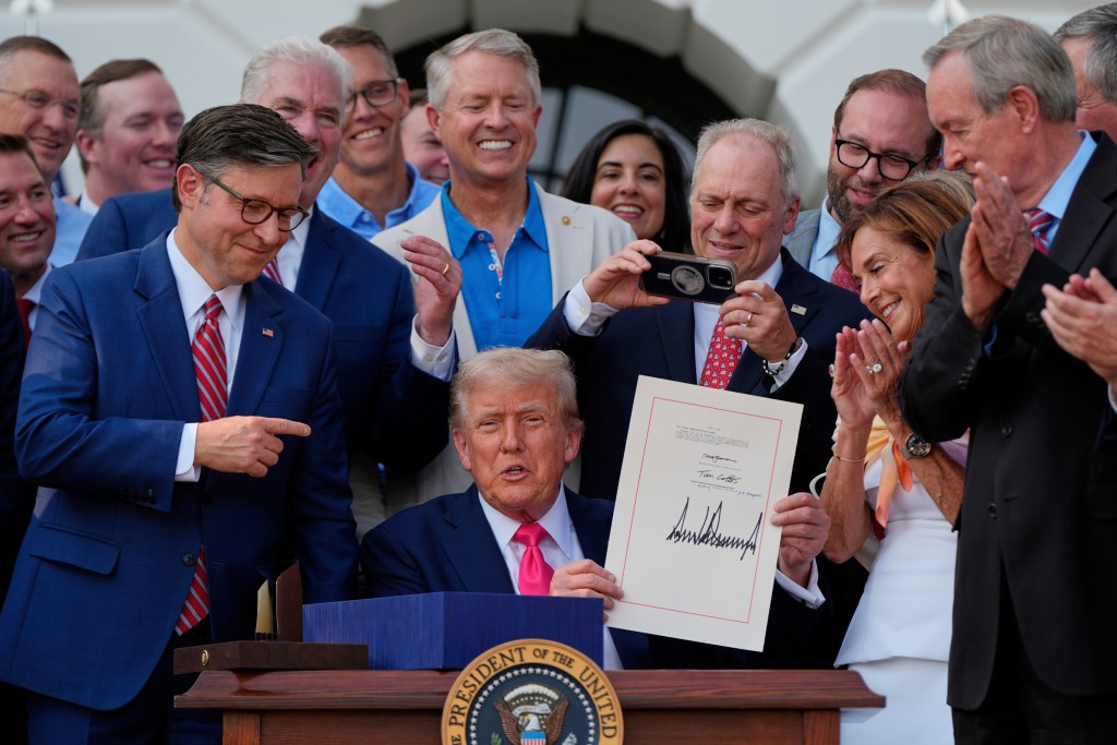 President Donald Trump holds up his signed bill. 